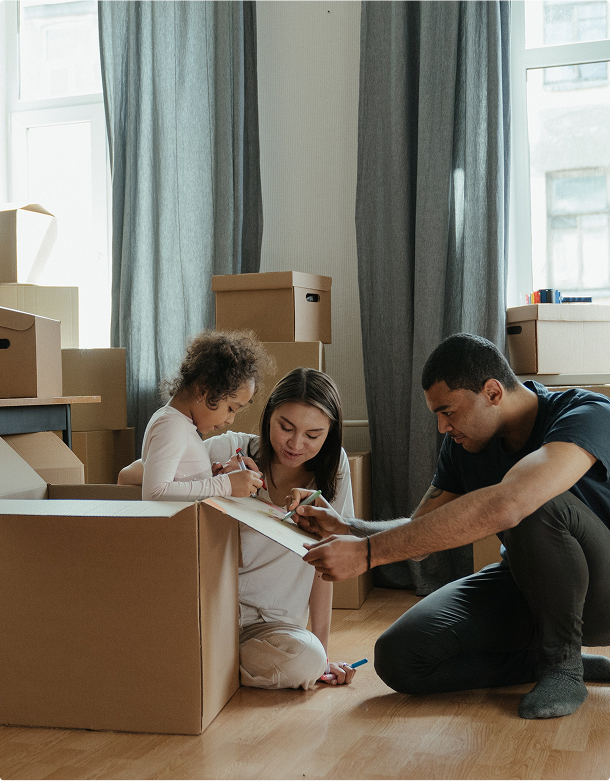 A family of three in an apartment, labeling boxes for a big move.