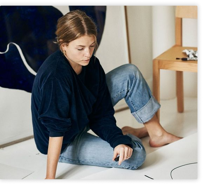 A woman sitting on the floor with a pen in her hand.