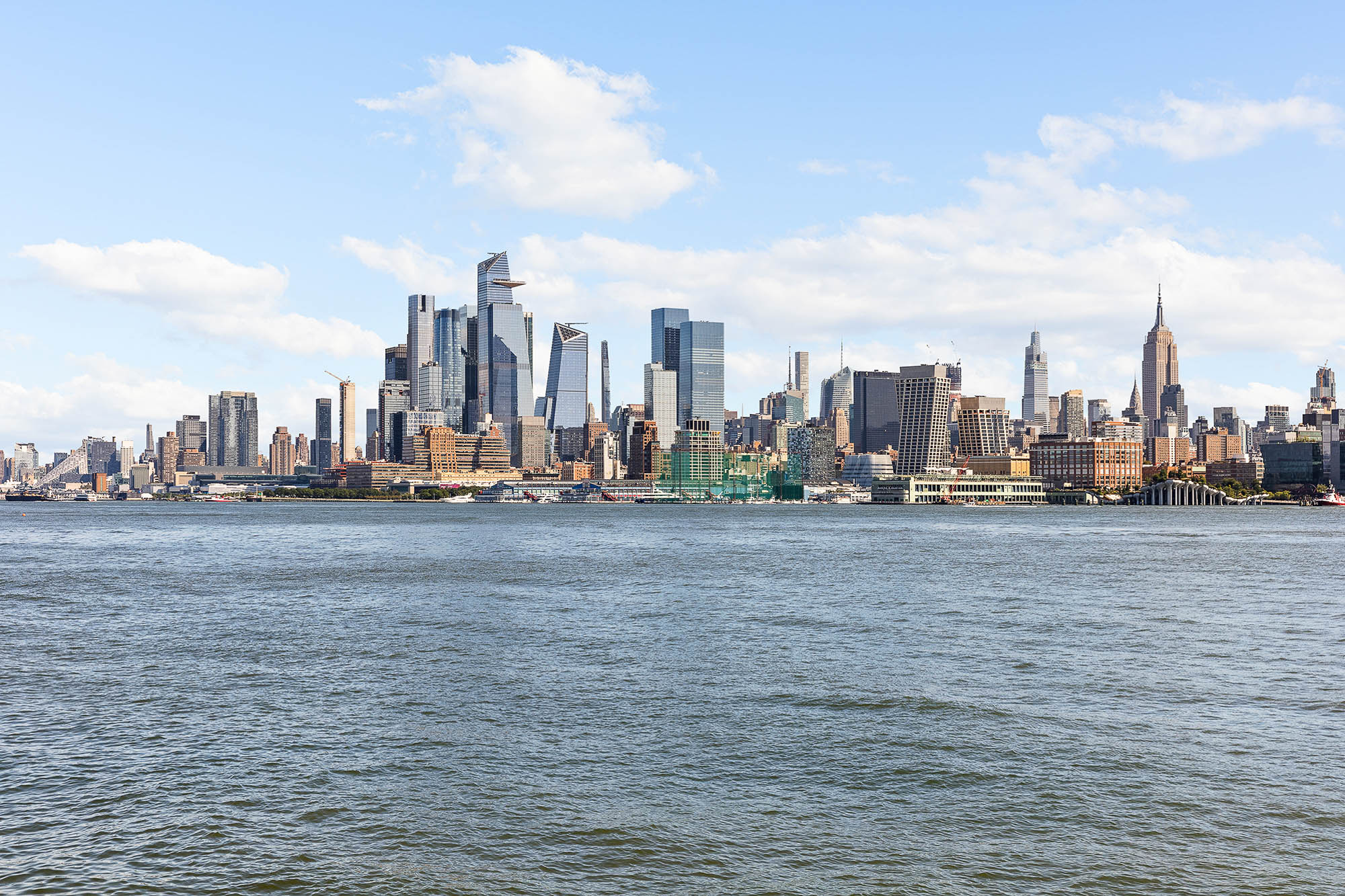 Panoramic view of the Manhattan skyline across the Hudson River from the Hoboken waterfront on a clear day.
